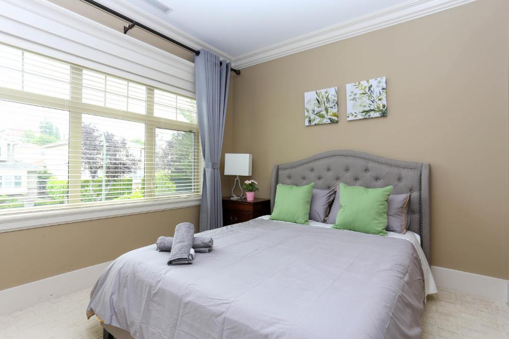 a bedroom with a large bed with green pillows at Grand House in Westside Vancouver in Vancouver