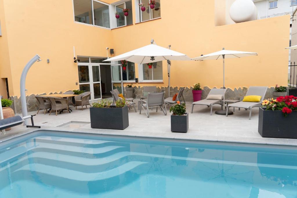 a swimming pool with chairs and umbrellas next to a building at Hôtel A casa di Maria Cicilia in Ghisonaccia