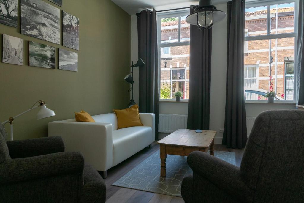 Una sala de estar con un sofá y dos sillas y una mesa. en Het Dokhuis, en Middelburg