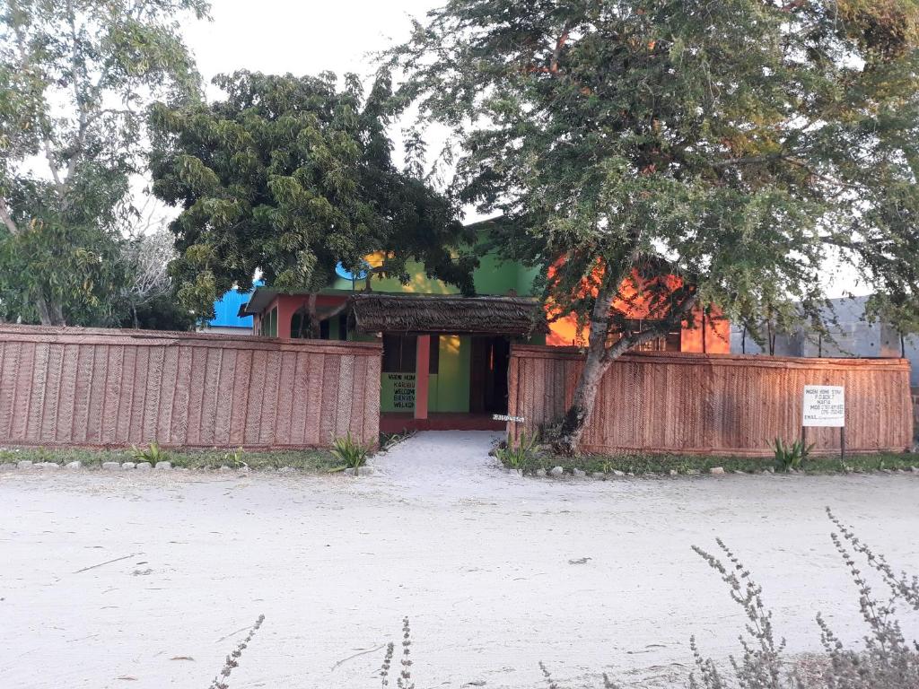 un bâtiment avec une clôture et un arbre devant lui dans l'établissement Mgeni Homestay, à Kilindoni