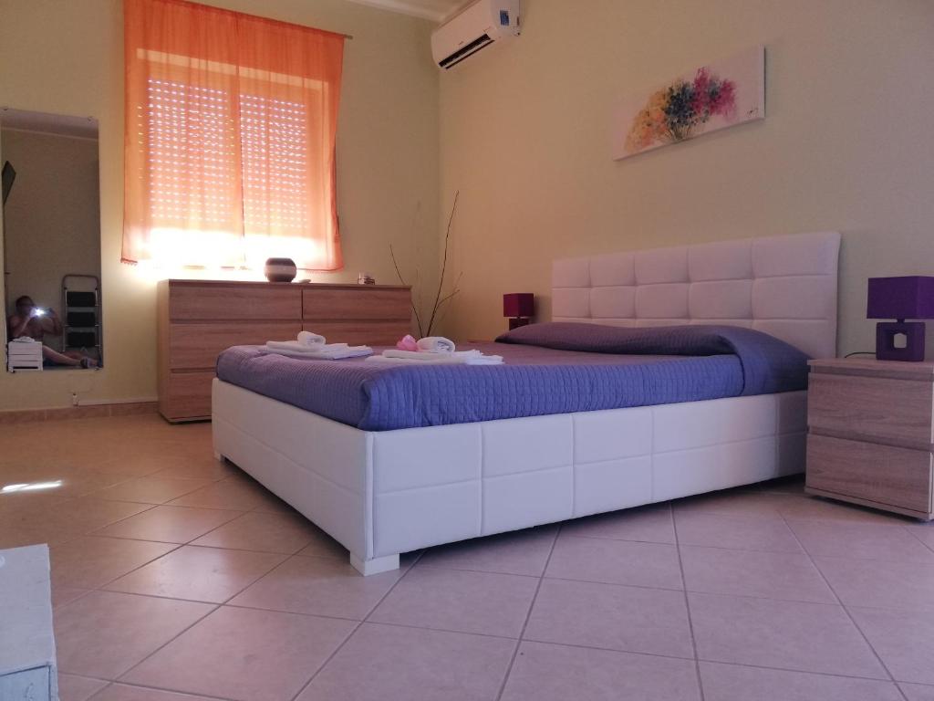 ein Schlafzimmer mit einem großen weißen Bett in einem Zimmer in der Unterkunft Heron House Apartments in Agnone Bagni