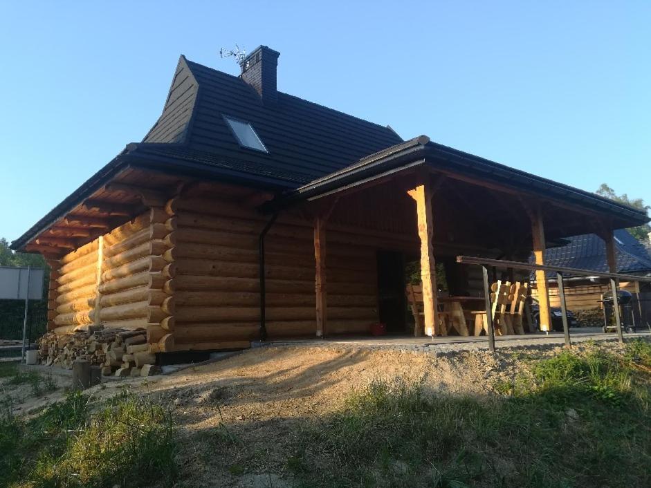 a log cabin with a black roof at POD BRZĘCZĄCYMI TRZMIELAMI in Kombornia