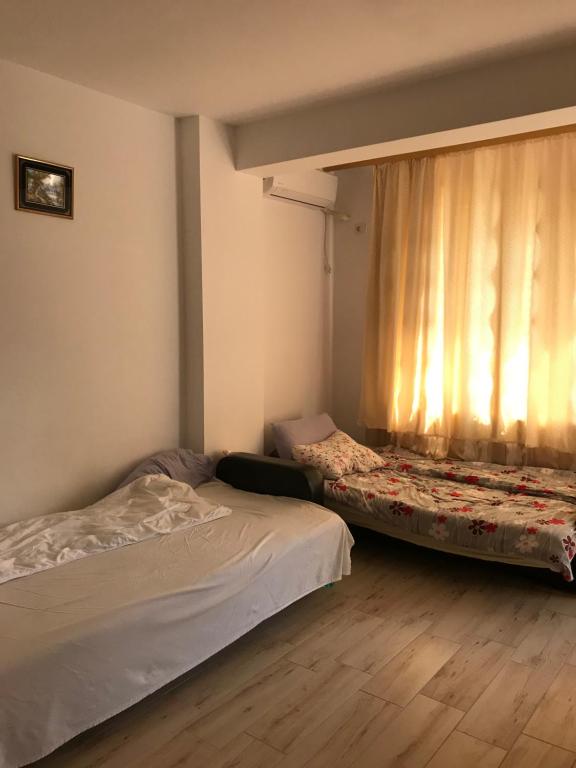 a bedroom with two beds and a window with curtains at Apartament Daniela in Năvodari