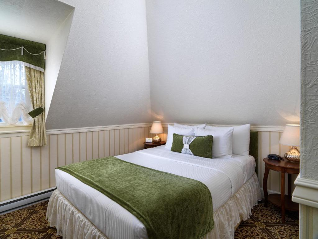 a bedroom with a large bed with a green blanket at Pendray Inn and Tea House in Victoria