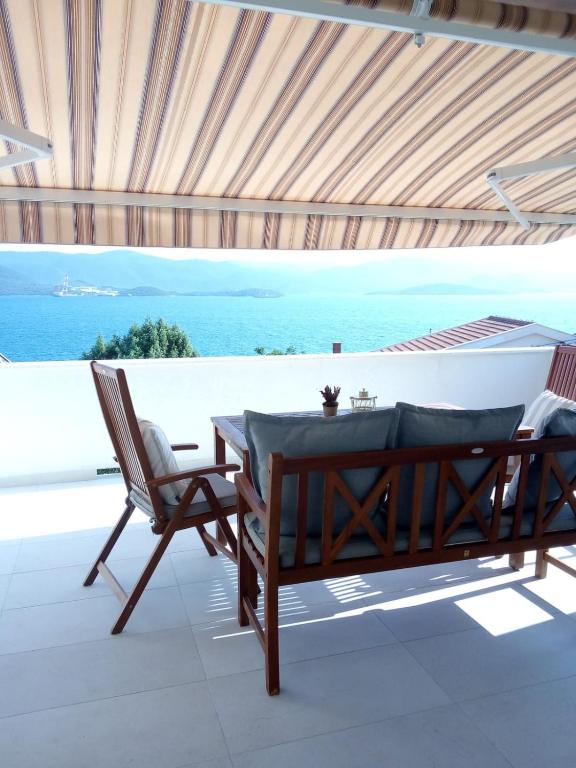 a table and chairs on a patio with a view of the ocean at Apartmani More Komarna in Komarna