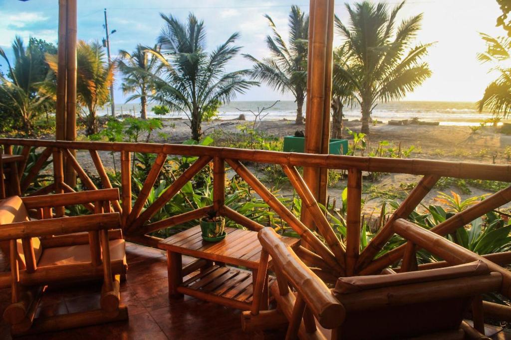 a balcony with a table and chairs on a beach at Seaside Garden Ecolodge Mompiche in Mompiche
