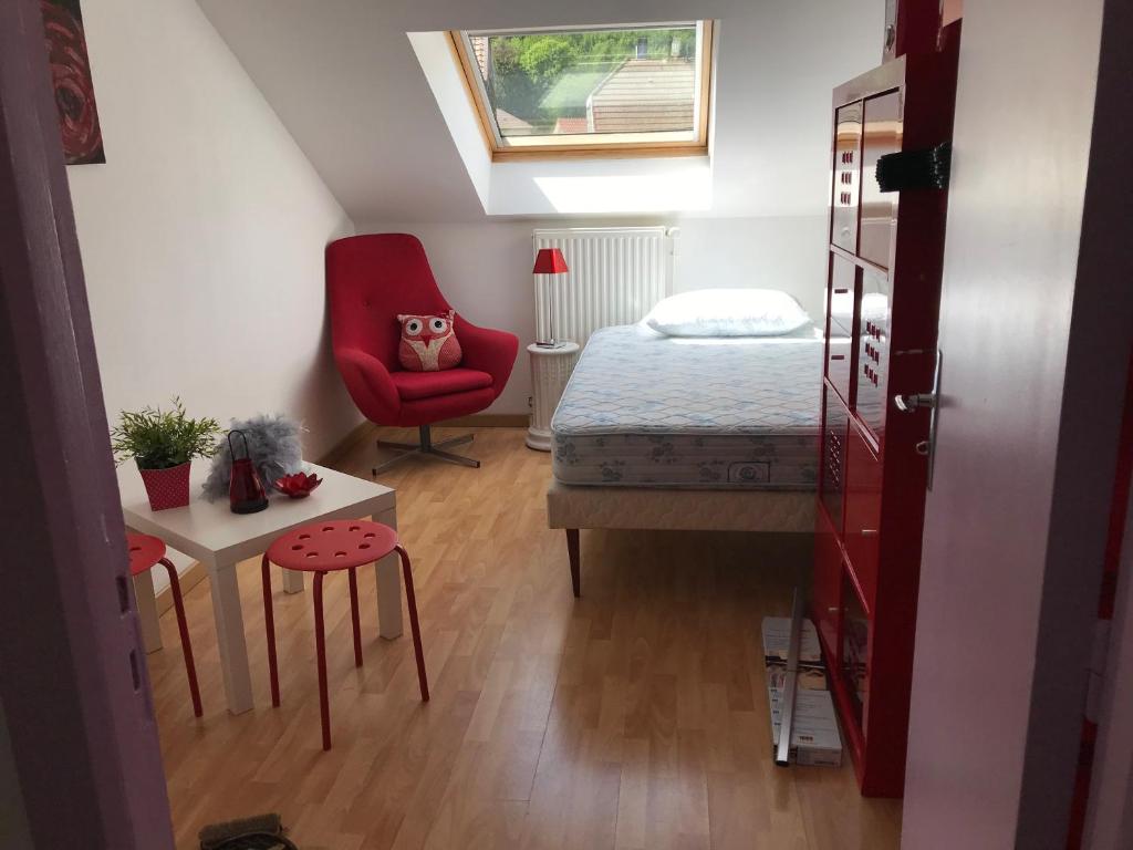 a small bedroom with a bed and a red chair at Résidence de l’ex hôtel des roches in Plancher-les-Mines