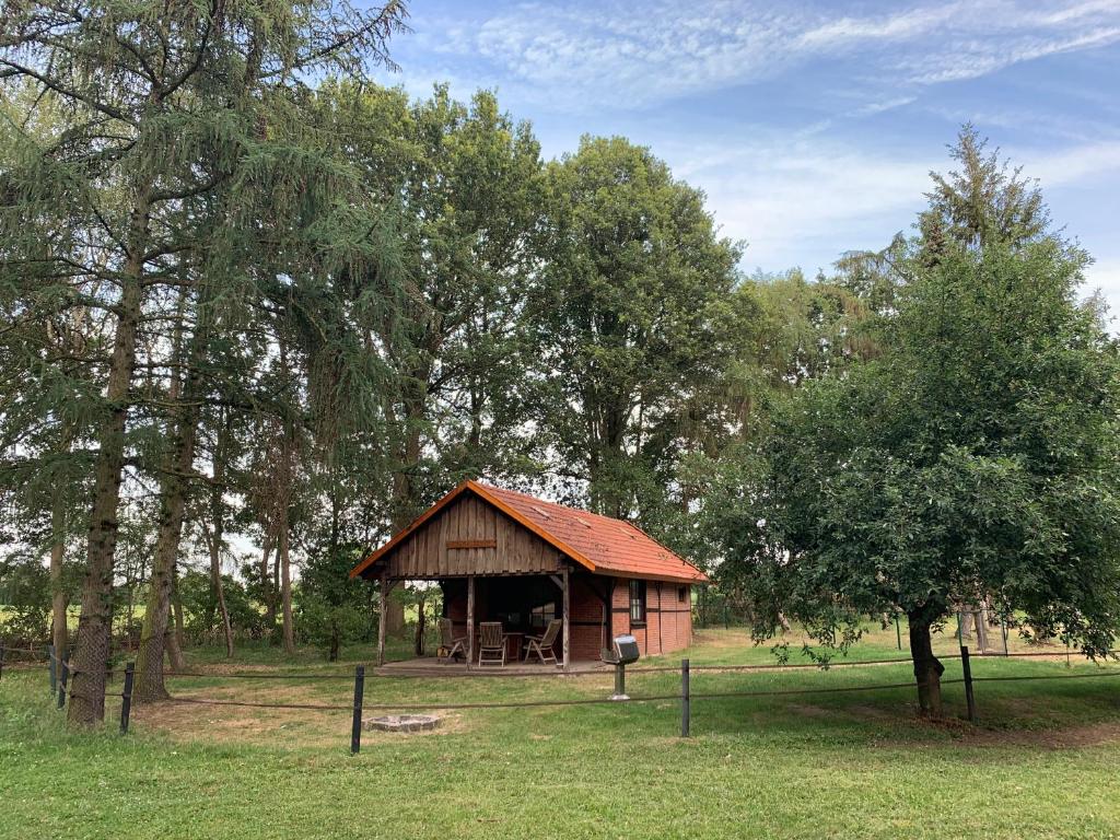 a small wooden cabin in a field with trees at Ferienhaus am Wäldchen in Uelsen