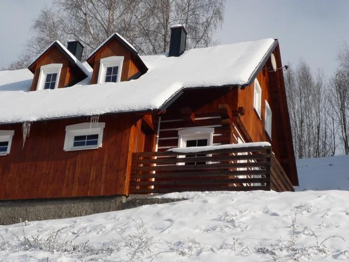 ein Holzhaus mit Schnee auf dem Dach in der Unterkunft Roubenka Zlatá Olešnice in Zlatá Olešnice