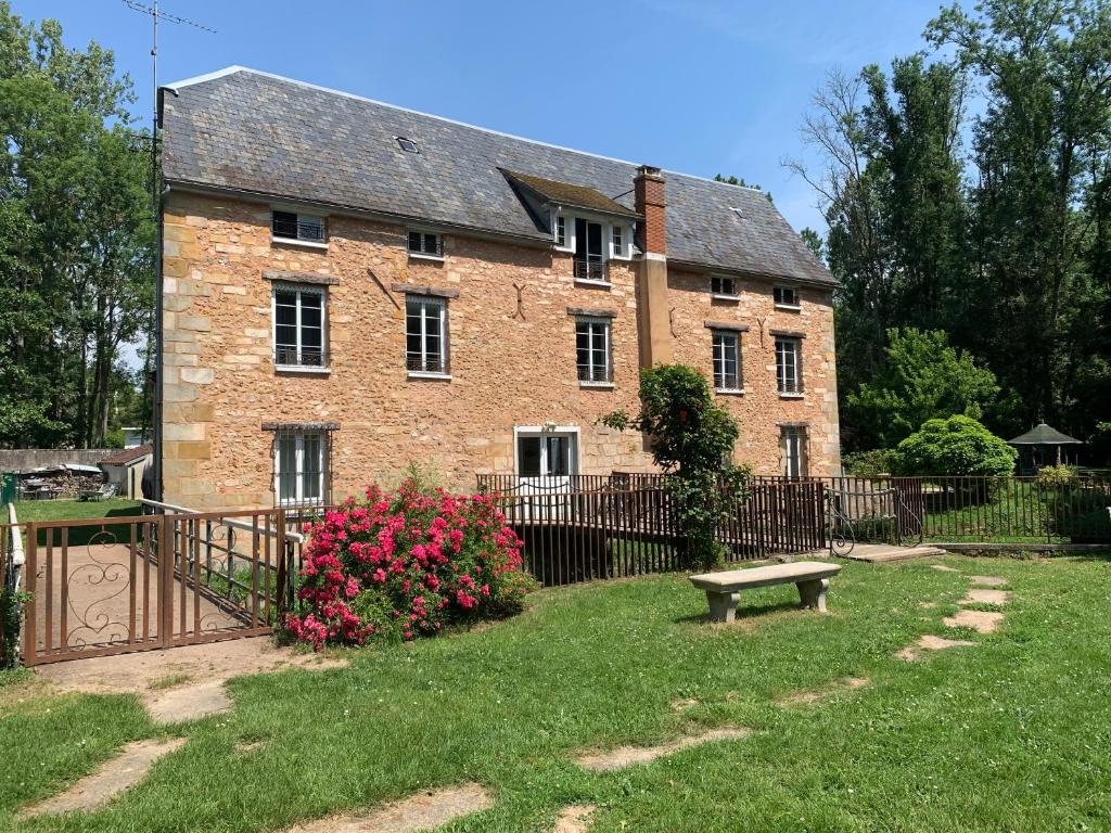 una gran casa de ladrillo con un banco en el patio en Le Moulin Bleu, en Saint Cyr-sous-Dourdan