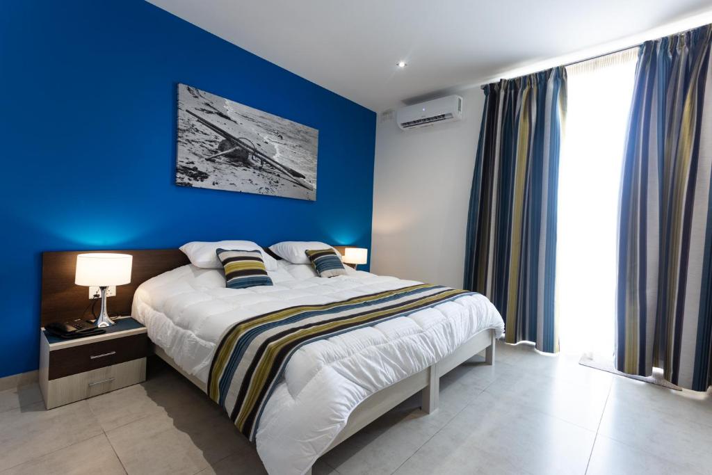 ein blaues Schlafzimmer mit einem Bett und einer blauen Wand in der Unterkunft The Shipwright's Lodge in Marsaxlokk