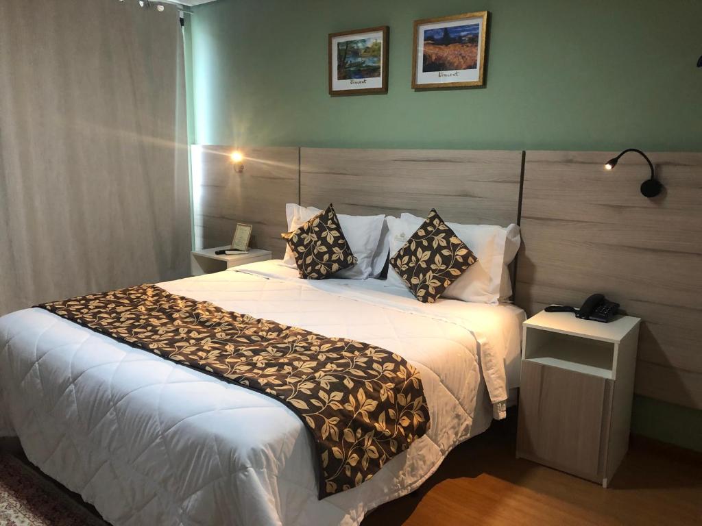 um quarto de hotel com uma cama grande com lençóis brancos e almofadas em Hotel & Pousada Princesa Isabel Rua Teresa em Petrópolis