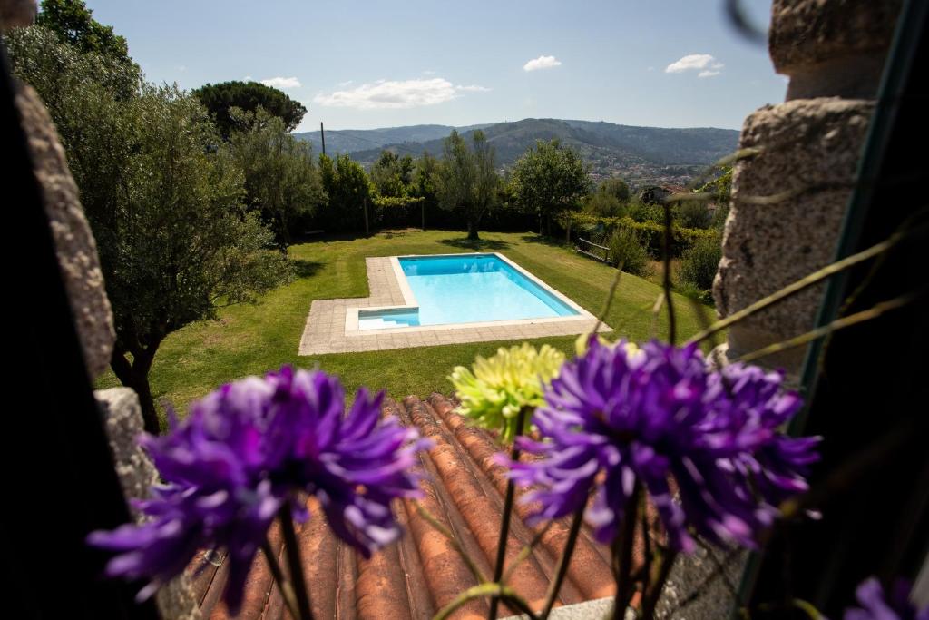 a garden with a swimming pool and purple flowers at Quinta do Castelo in Arcos de Valdevez