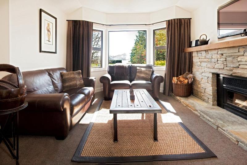 sala de estar con muebles de cuero y chimenea en Pembroke Lodge, en Wanaka