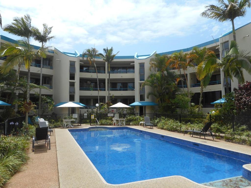 Placid Waters Holiday Apartments في Bongaree: فندق فيه مسبح امام مبنى