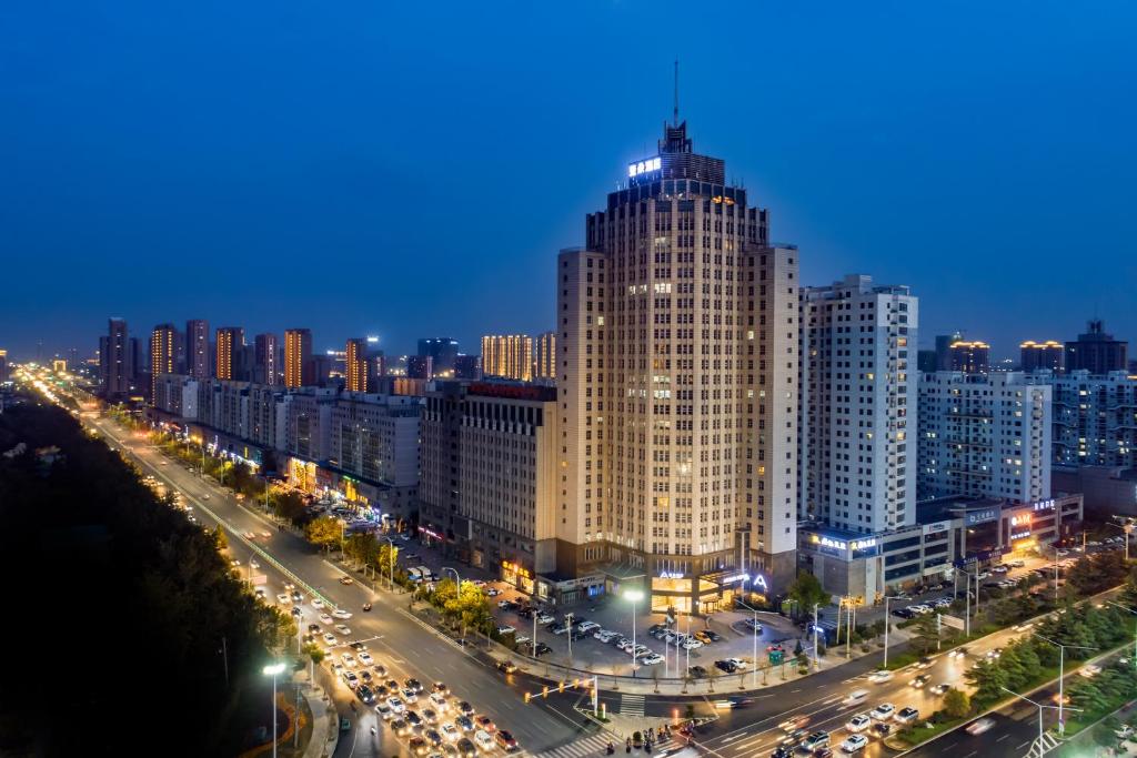 a city skyline with a tall building at night at Atour Hotel Weifang Jinma Road City Hall in Weifang