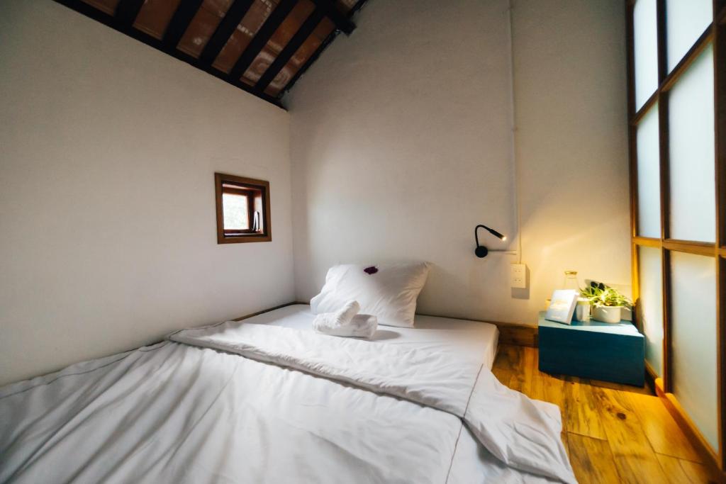Un dormitorio con una cama con sábanas blancas y una ventana. en a-mâze house, en Hue