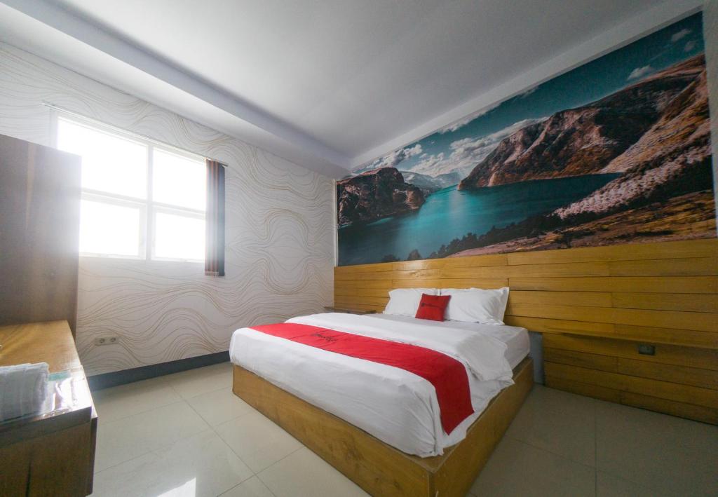 a bedroom with a large bed with a painting on the wall at RedDoorz Plus Syariah @ Pentadio Gorontalo in Gorontalo