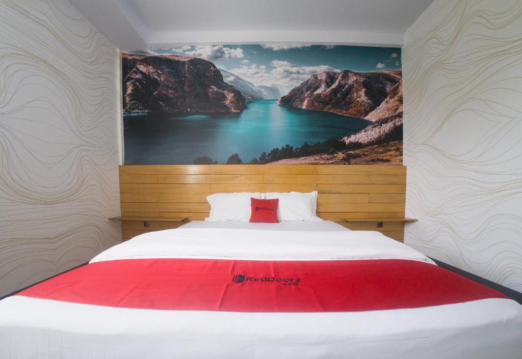 Un dormitorio con una cama grande con un cuadro en la pared. en RedDoorz Plus Syariah @ Pentadio Gorontalo, en Gorontalo