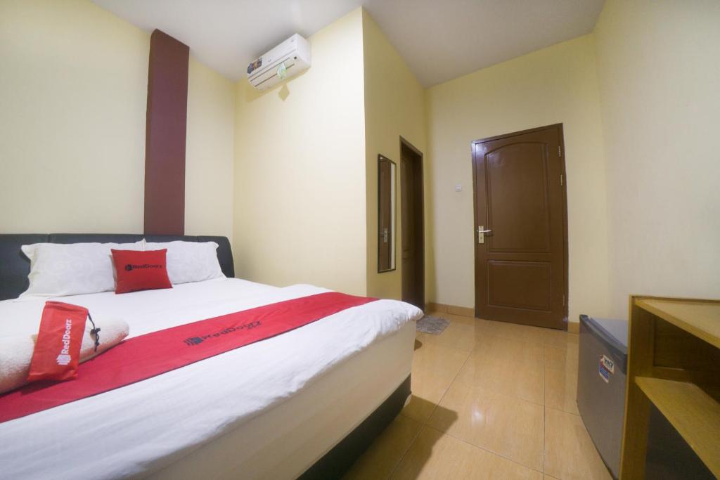 um quarto com uma cama grande e almofadas vermelhas em RedDoorz near TVRI Gorontalo em Telaga