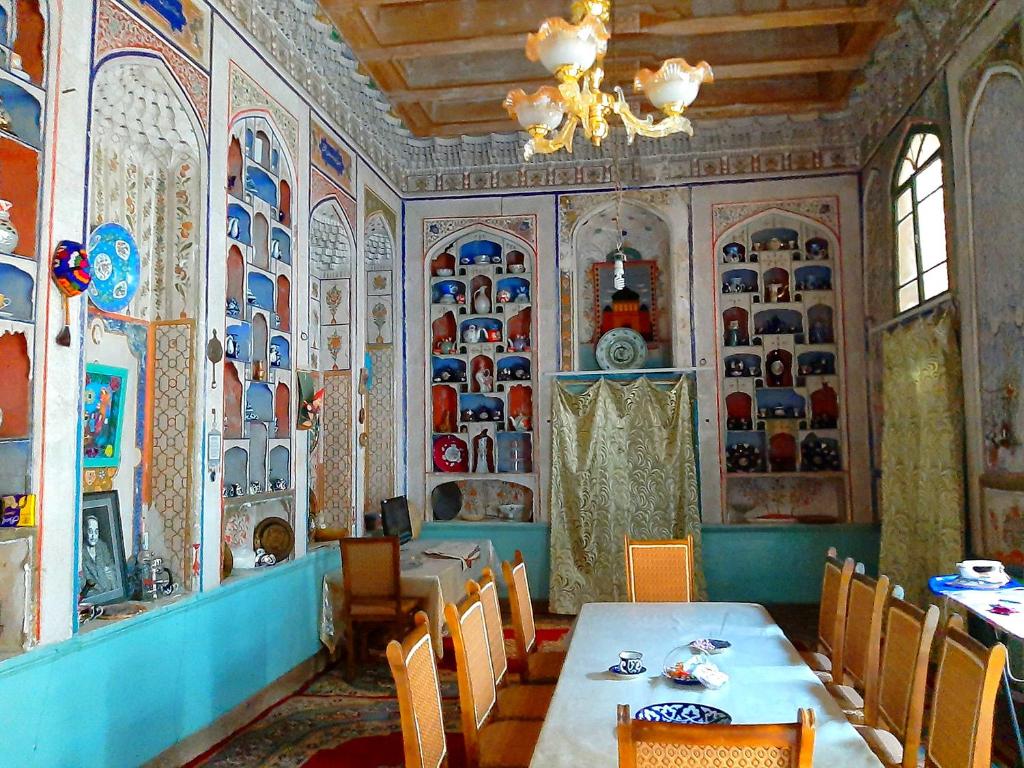 a dining room with a table and chairs and plates on the wall at Art Guest House USTO in Bukhara