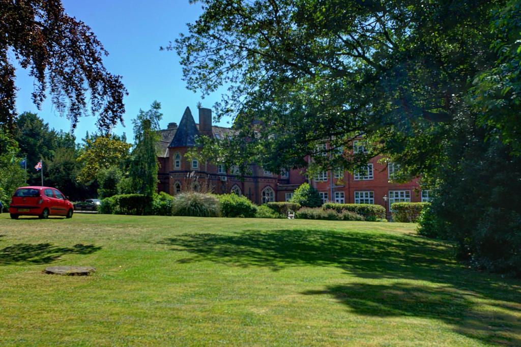 a red car parked in front of a large house at Best Western Abbots Barton Hotel in Canterbury