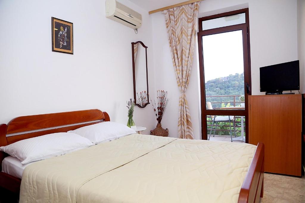 - une chambre avec un lit, une télévision et une fenêtre dans l'établissement Apartments Ardura, à Petrovac na Moru