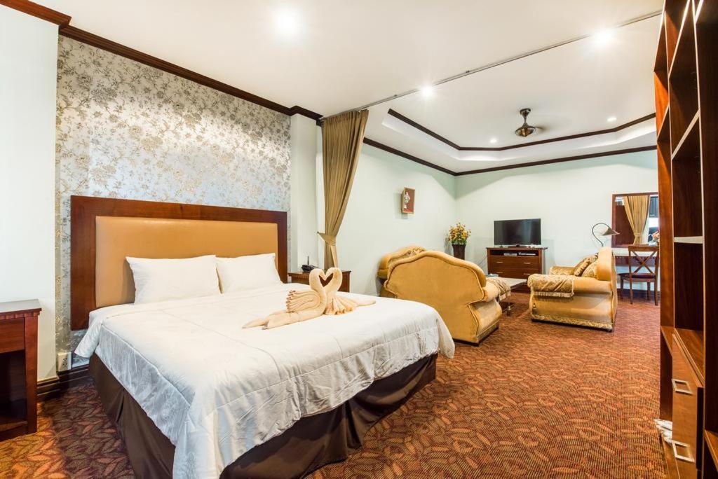una habitación de hotel con una cama grande y una silla en Excellency Apartment, en Vientiane