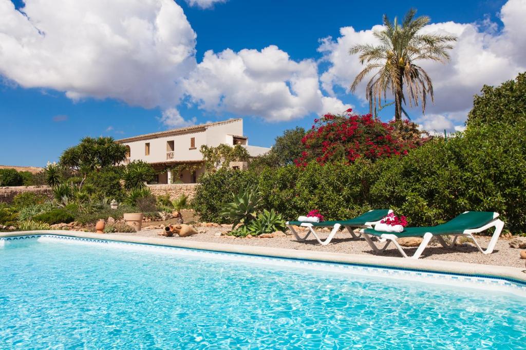 a swimming pool with two chairs and a house at Finca Can Paulino in Llucmajor