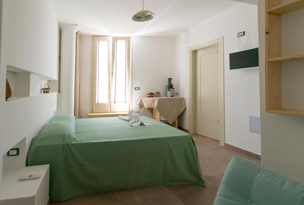a bedroom with a green bed and a table at Il Galletto bb in Patù