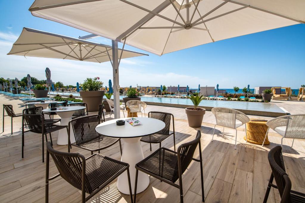 a patio with tables and chairs and umbrellas at Arena Grand Kazela Camping Homes in Medulin