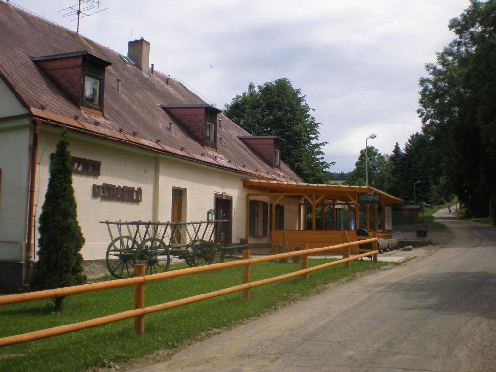 a house with a wooden fence next to a road at Penzion u Hradilů in Vrbno pod Pradědem