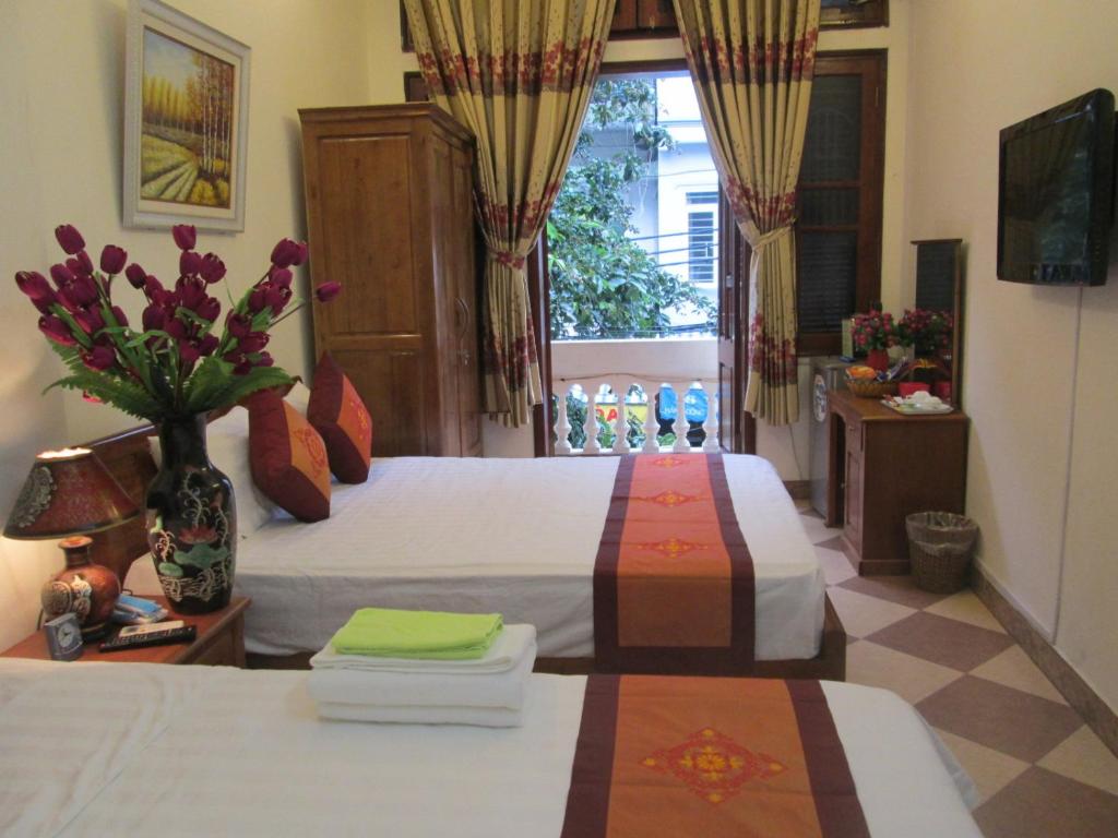 a bedroom with two beds and a vase of flowers at Hanoi Ecogreen Hostel in Hanoi