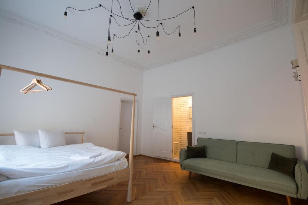 ein Schlafzimmer mit einem Bett, einem Sofa und einem Kronleuchter in der Unterkunft George Enescu Suites in Bukarest