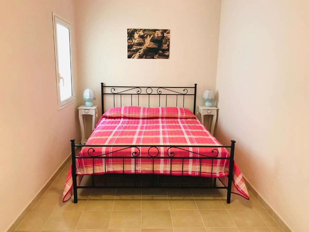 una camera con un letto con una coperta rossa e rosa di Nilla Apartments a Noto Marina