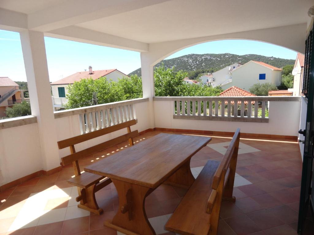a large balcony with a wooden table and benches at Andrijas Apartments in Tribunj