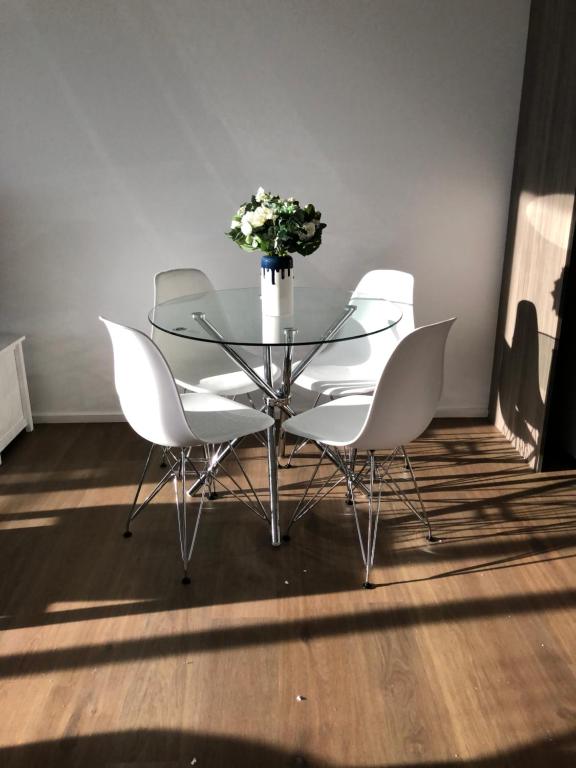 une table en verre avec des chaises blanches et un vase de fleurs dans l'établissement Skyview Apartment in Liverpool, à Liverpool