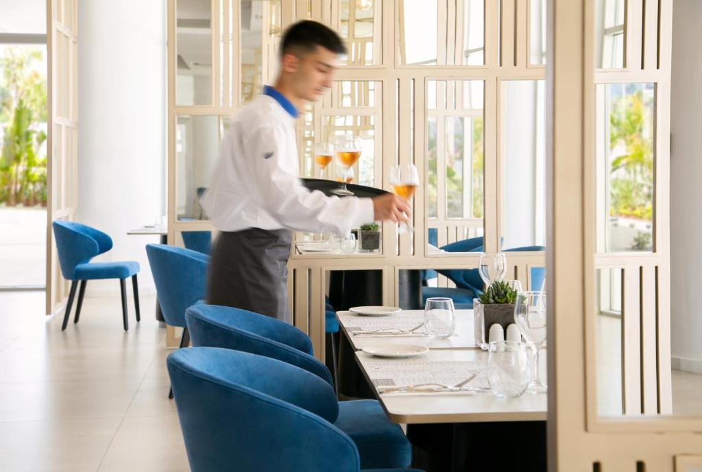 a man standing at a table in a restaurant at NissiBlu Beach Resort in Ayia Napa