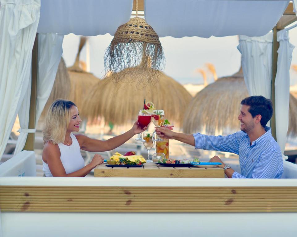 a man and woman sitting at a table with a drink at Gran Hotel Guadalpín Banus in Marbella
