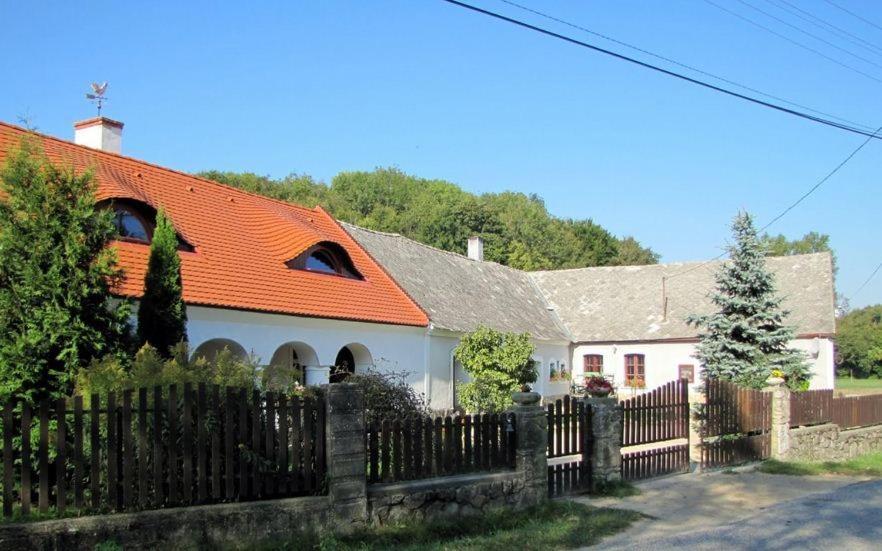 una casa blanca con techo naranja y valla en Sörényes Udvarház, en Pénzesgyőr