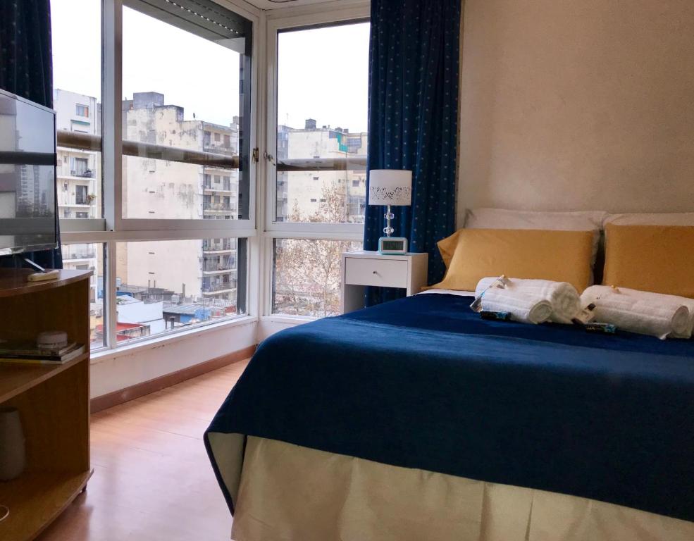 a bedroom with a blue bed and a large window at Apartamento Bulnes y Calle Corrientes in Buenos Aires