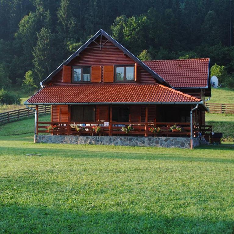 a large house with a grass field in front of it at Ivola Vendégház in Izvoare
