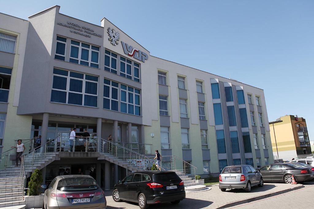 a large building with cars parked in a parking lot at Pokoje Gościnne WSAP in Ostrołęka