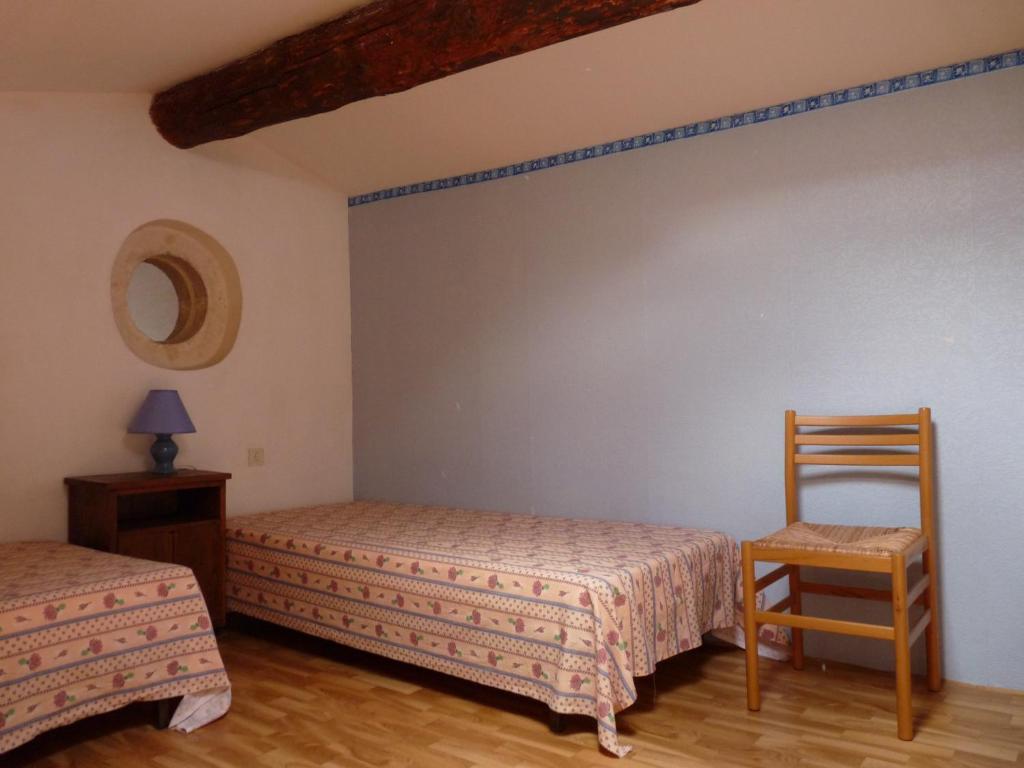 1 Schlafzimmer mit 2 Betten und einem Holzstuhl in der Unterkunft Les Esclots , Nîmes, Gîtes 4 personne in Générac