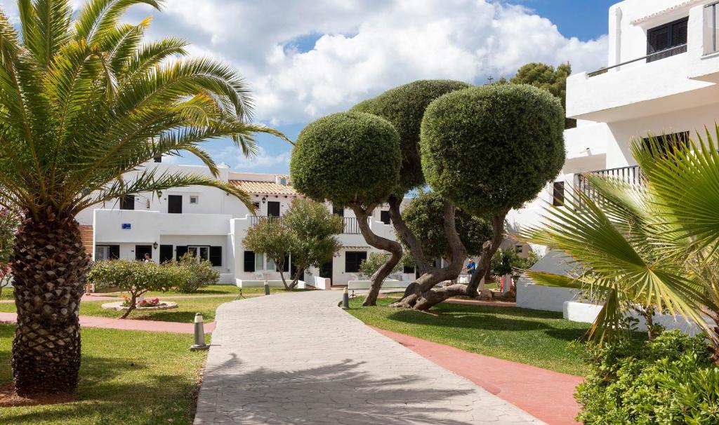 een loopbrug voor een gebouw met bomen bij Hotel Palia Dolce Farniente in Cala d´Or