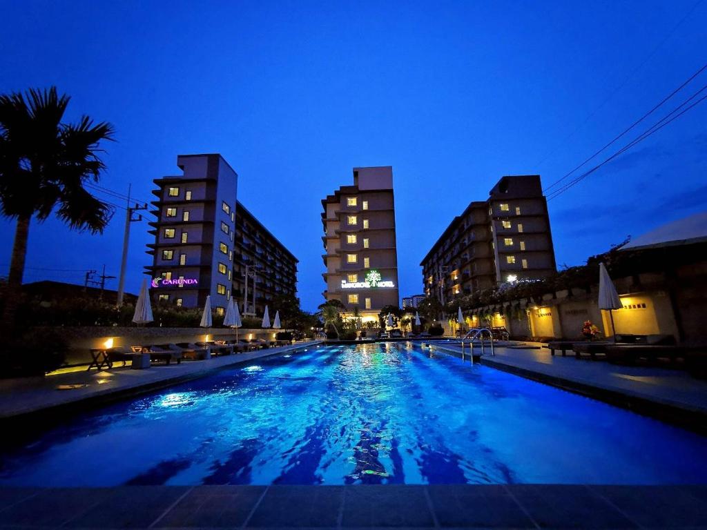 a large swimming pool at night with two tall buildings at The Mangrove Hotel in Na Jomtien