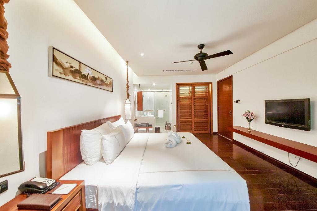 a bedroom with a large white bed and a television at Ocean Sonic Resort Sanya in Sanya