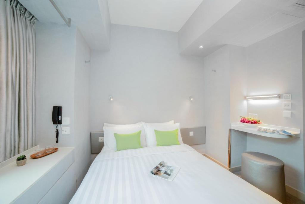a bedroom with a large white bed with green pillows at Hotel Ease Mong Kok in Hong Kong