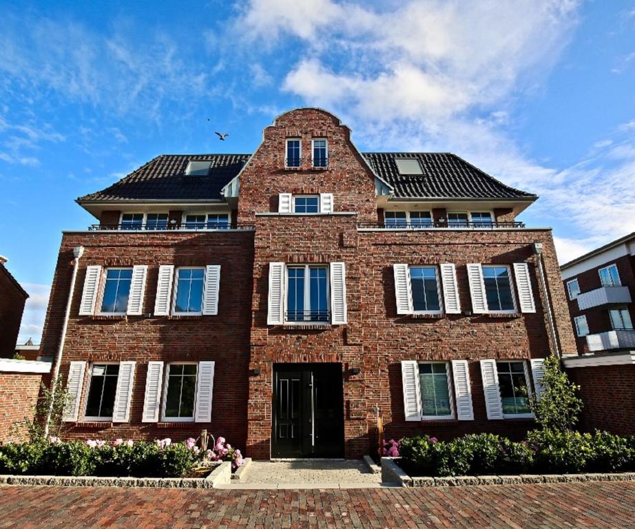 ein Backsteingebäude mit weißen Fenstern und einem Dach in der Unterkunft Villa Petersen "Himmel & Meer" in Wangerooge