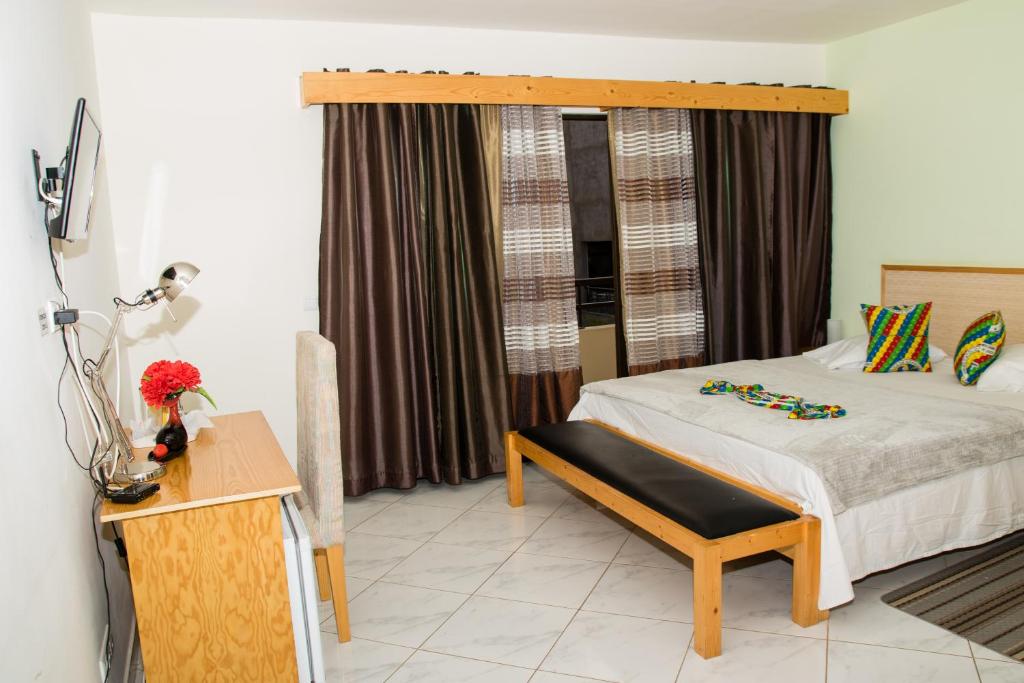 1 dormitorio con cama con banco y ventana en LT Aparthotel, en Praia